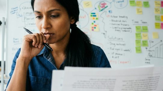 Professionnelle concentrée analysant des objectifs SEO devant un tableau de planification stratégique