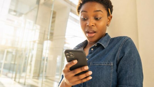 Femme surprise regardant son smartphone en extérieur