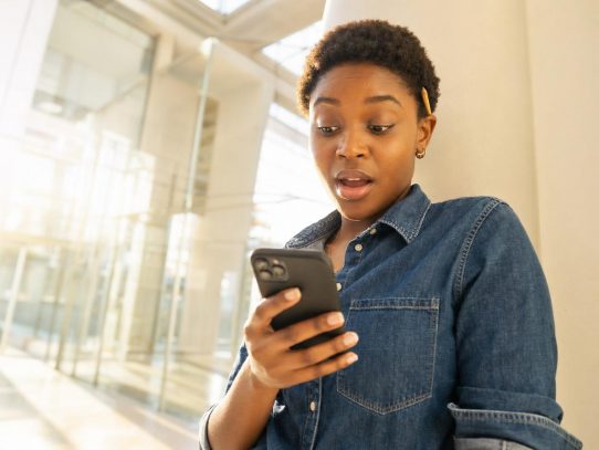 Femme surprise regardant son smartphone en extérieur