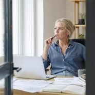 Femme réfléchissant devant ordinateur portable au bureau