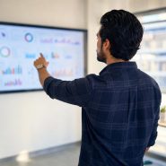 Homme pointant des graphiques sur écran en bureau