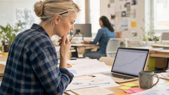 Femme analysant graphiques sur ordinateur portable au bureau